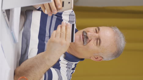 Vertical-video-of-Home-office-worker-old-man-shopping-on-the-phone.